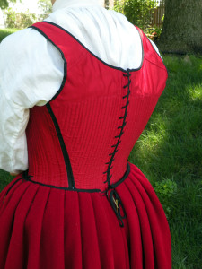 This petticoat laced closed at the back. The pleats are knife pleats, with a layer of wool pleated in with the outer fabric. The waistband is bound around the raw edges of the pleats.